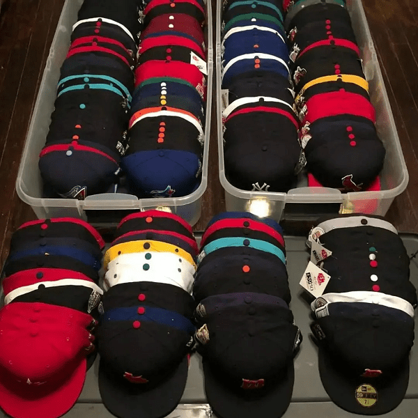 Assorted headgear liquidation pallet featuring bulk hats, caps, beanies, and assorted branded accessories stacked for wholesale resale inventory.