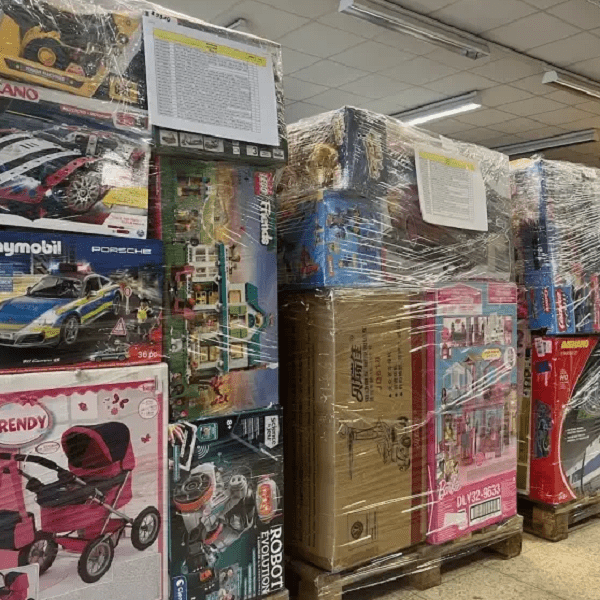 Games liquidation pallets mixed with assorted toys stacked in bulk boxes, wholesale resale inventory for discount retail and online sellers
